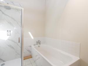 un bagno bianco con vasca e doccia di South Barn Cottage a Faringdon