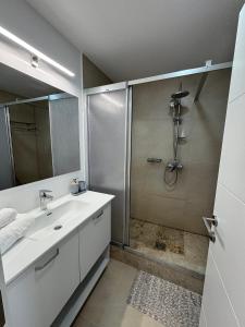 a white bathroom with a shower and a sink at Gabriela Blaxy Apartamente in Olimp
