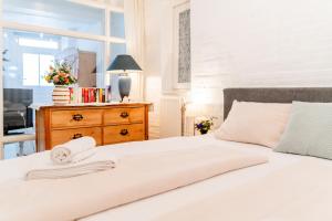 a bedroom with a white bed with a dresser and a window at Altstadtapartment- Historischer Charme trifft modernen Komfort zentral & gemütlich mit Parkplatz! in Niederdorla