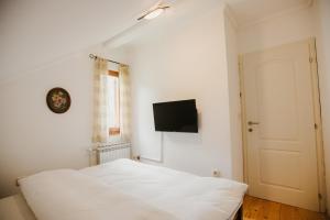 a bedroom with a white bed and a flat screen tv at Vikendica Tara in Risovac
