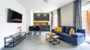 a living room with a blue couch and a table at Baltic Waves Resort, Sun & Snow in Międzyzdroje