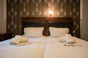 a large white bed with two towels on it at Toti Boutique Rooms in Kalabaka