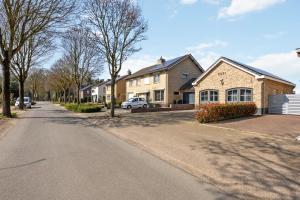 a residential street with houses and a car parked on the road at B&B Oos Heim in Maria-Hoop
