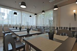 a dining room with tables and chairs and windows at Zen Hotel Versilia in Marina di Pietrasanta