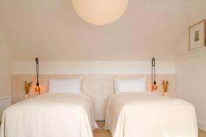 two beds in a room with white sheets at Kelp Lodge in Doolin