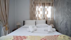 a white bed with white pillows and a window at Toti Boutique Rooms in Kalabaka