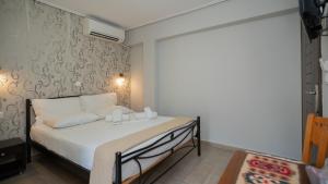 a small bedroom with a bed with white sheets at Toti Boutique Rooms in Kalabaka