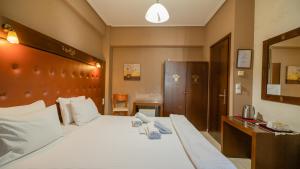 a bedroom with a large white bed with a wooden headboard at Toti Boutique Rooms in Kalabaka