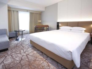 una camera con un grande letto bianco e una sedia di The Cypress Mercure Hotel Nagoya a Nagoya