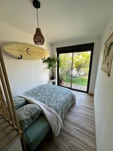 a bedroom with a bed and a surfboard on the wall at VILLA FENG SHUI déco bali St Aygulf 3 chambres in Saint-Aygulf