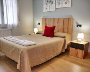 a bed with a red pillow and two towels on it at Pensión Pamplonabeds in Pamplona