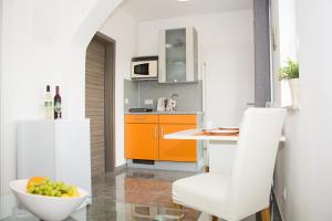 una cucina arancione e bianca con una ciotola di frutta di Helis Gästezimmer a Kirchbach in Steiermark