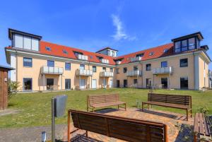 Dos bancos frente a un edificio grande en Peenemünde, Seglerhafen_SB_Slup 12 15, en Peenemünde