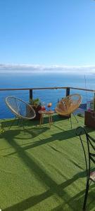 two chairs and a table on a lawn with the ocean at Las Vistas Apartament in La Rambla