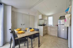 a kitchen with a table with yellow plates on it at Camping 4 étoiles - Parc aquatique - eeiaeg in Saint-Jean-de-Monts