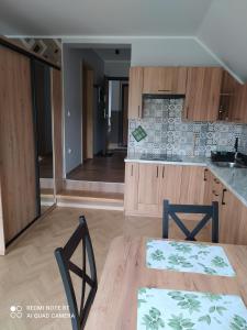 eine Küche mit Holzschränken und einem Tisch und Stühlen in der Unterkunft Domek NA SKRAJU WSI, APARTAMENTY in Górki Wielkie + 9 Fotos