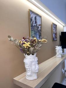 Eine weiße Vase mit Blumen im Regal. in der Unterkunft Casa A Pupidda vicino al mare in Avola