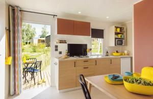 Una cocina y un comedor con mesa y sillas. en Camping 4 étoiles - Parc aquatique - eeiaia, en Olonne-sur-Mer