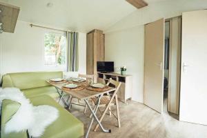 una sala de estar con una mesa y un sofá en Camping 3 étoiles - Parc aquatique - eeibbf, en Fouesnant