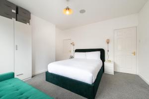 a bedroom with a white bed and a green couch at Central 2 BR Cosy House in Rugby