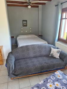 a couch in a room with a bed and a window at SPITIKARIOTIKO Garden home in Mesochórion