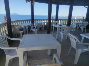 a table and chairs on a porch with a view of the ocean at Pinwheel Hostel Vlora & Rooftop Bar in Vlorë
