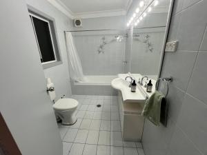 a white bathroom with a toilet and a sink at Airport Guesthouse in Sydney +8 photos