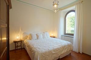Un dormitorio con una cama blanca y una ventana. en Tenuta d'Elci - Relax e Piscina nel Bosco, en Casteldelci 27 fotos más