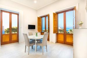 ein Esszimmer mit Tisch und Stühlen und Fenstern in der Unterkunft Maramia Luxury Apartment in Sant'Agnello