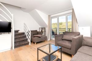 a living room with a couch and chairs and a tv at Wohnung Peper in Juist
