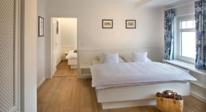 a white bedroom with a bed and a window at Penthouse Ferienwohnung Penthuus in Juist