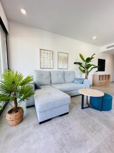 ein Wohnzimmer mit einem blauen Sofa und einem Tisch in der Unterkunft Beleef Spanje new luxury apartment with sea view in Orihuela