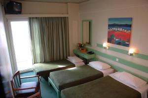 una camera d'albergo con tre letti e uno specchio di Amalia a Salonicco