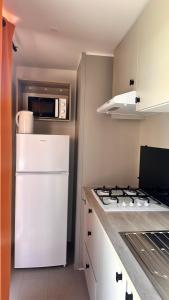 a kitchen with a white refrigerator and a stove at Camping Villa Park Zambujeira do Mar in Zambujeira do Mar