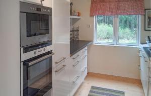 a kitchen with white appliances and two windows at Lovely Home In Rimforsa With Lake View in Rimforsa +5 photos