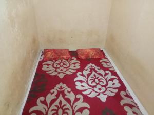 a small room with a red and white bed at Penginapan Syari'ah Parak Anau in Tabing