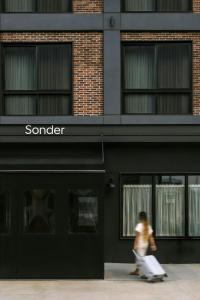 a woman walking down a sidewalk in front of a store at Sonder by Marriott Bonvoy The Dutch Apartments Long Island City in Long Island City
