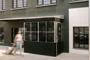 a man walking past a building with a revolving door at The Industrialist Hotel Brooklyn in Brooklyn