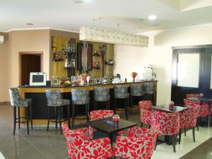um restaurante com cadeiras vermelhas e brancas e um bar em Kornilios Palace em Anchialos