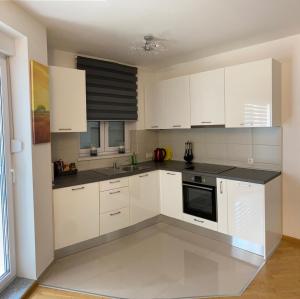 a white kitchen with white cabinets and a sink at Apartman Omazić in Livno