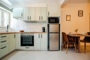 a kitchen with white cabinets and a table and a refrigerator at Kantounata Apartment in Lefkimmi