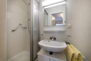 un bagno bianco con lavandino e doccia di Hotel Austria a Bad Hofgastein Altre 17 foto