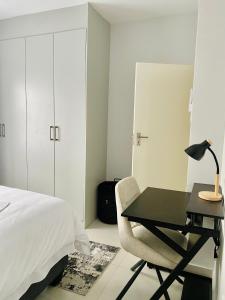 ハボローネにあるFirst Apartmentsのベッドルーム1室(ベッド1台、ランプ付きデスク付) +1枚の写真