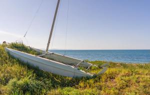 un bateau assis dans l'herbe sur la plage dans l'établissement 5 Bedroom Stunning Apartment In Trappeto, à Trappeto