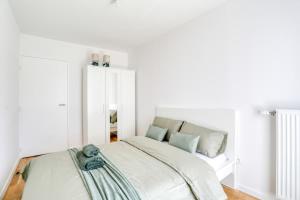 a white bedroom with a bed and a mirror at Home Sweet Home in Bezons