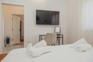 Un dormitorio con una cama blanca con un televisor en la pared. en Casa Nolimi, en Fažana