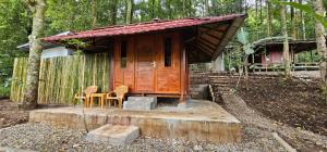a small wooden house with chairs and a table at Rasamala Camp in Pengalongan