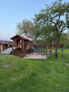 a playground with a house and a slide at Pokoje Gościnne Pod Szyszkami in AdamÃ³w