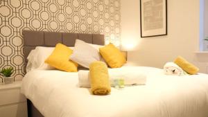 a white bed with yellow pillows and a dog on it at Lovely 2 Bed Apartment w Garden near Northampton in Earls Barton