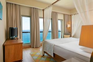 a bedroom with a bed and a tv and windows at Xanadu Island in Akyarlar